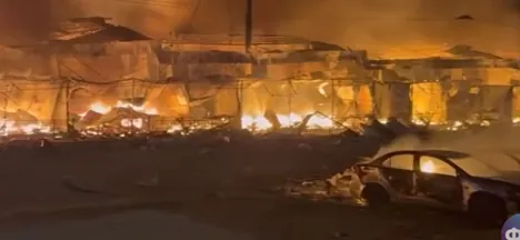 Horiace budovy a zhorené auto v noci