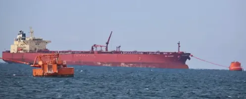 Červený nákladný tanker na mori s oranžovou plošinou v popredí